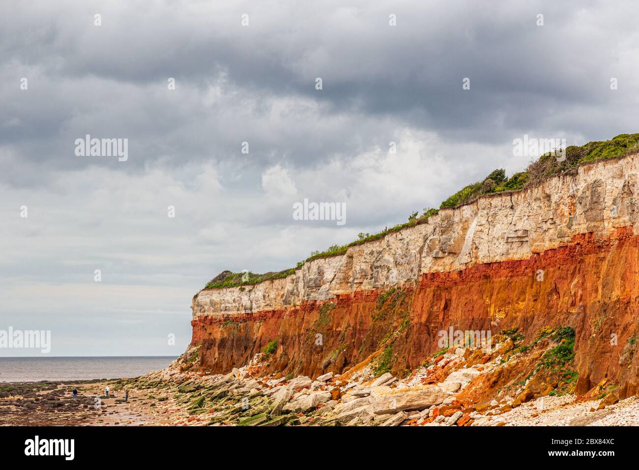 Orangene, rote und weiße Sedimentgesteine am Strand in Hunstanton, Norfolk, East Anglia, Großbritannien. Stockfoto