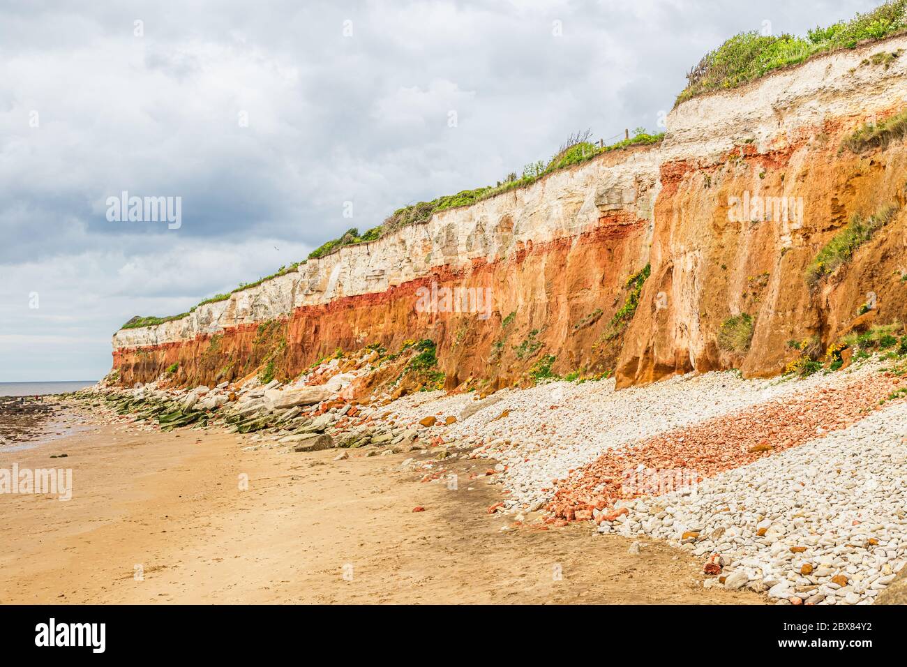 Orangene, rote und weiße Sedimentgesteine am Strand in Hunstanton, Norfolk, East Anglia, Großbritannien. Stockfoto