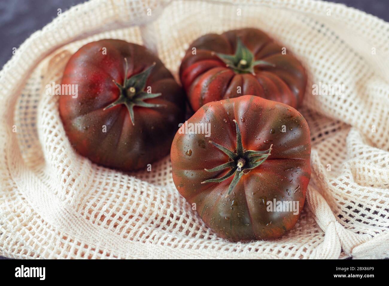 Schwarze Tomaten in wiederverwendbarem Einkaufstasche, plastikfrei, Zero Waste Konzept Stockfoto