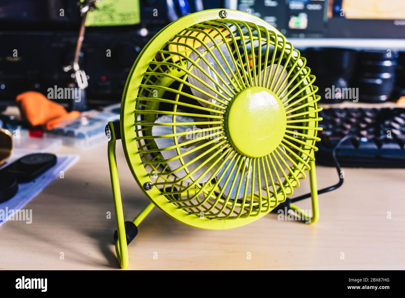 Ein kleiner Desktop-USB-Lüfter, Desktop-Computer und Elemente im Hintergrund. Stockfoto