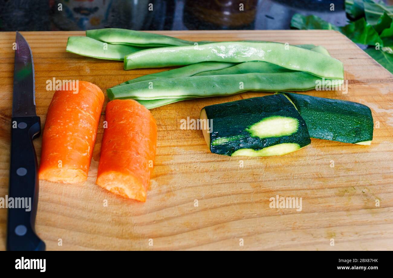 Ein Holzschneidebret, frisches Gemüse - Zucchini, Karotten und Bohnen. Stockfoto