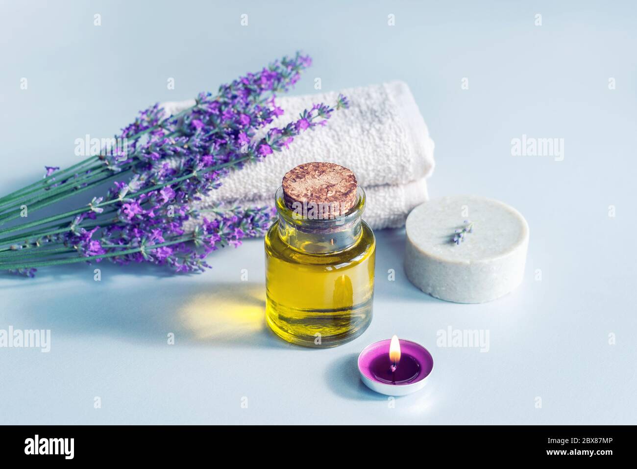 Spa-Produkte, Seife, Massageöl, Kerze und Handtuch, Lavendelblüten auf weißem Hintergrund. Stockfoto