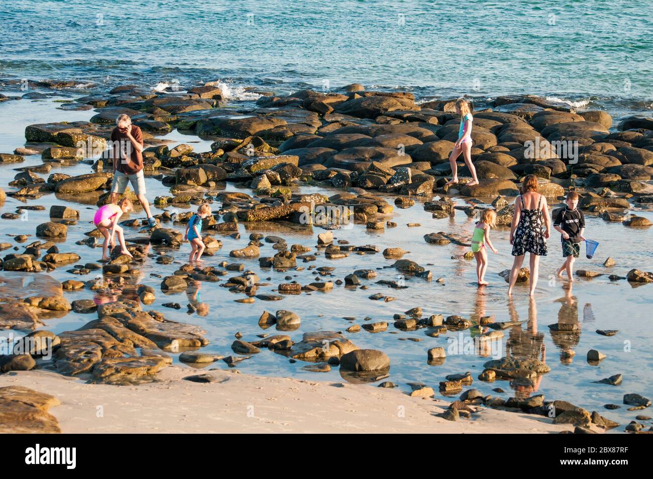 Familien, die in den Felsenpools von Bulcock Beach, Caloundra, Sunshine Coast, Queensland, Australien waten Stockfoto
