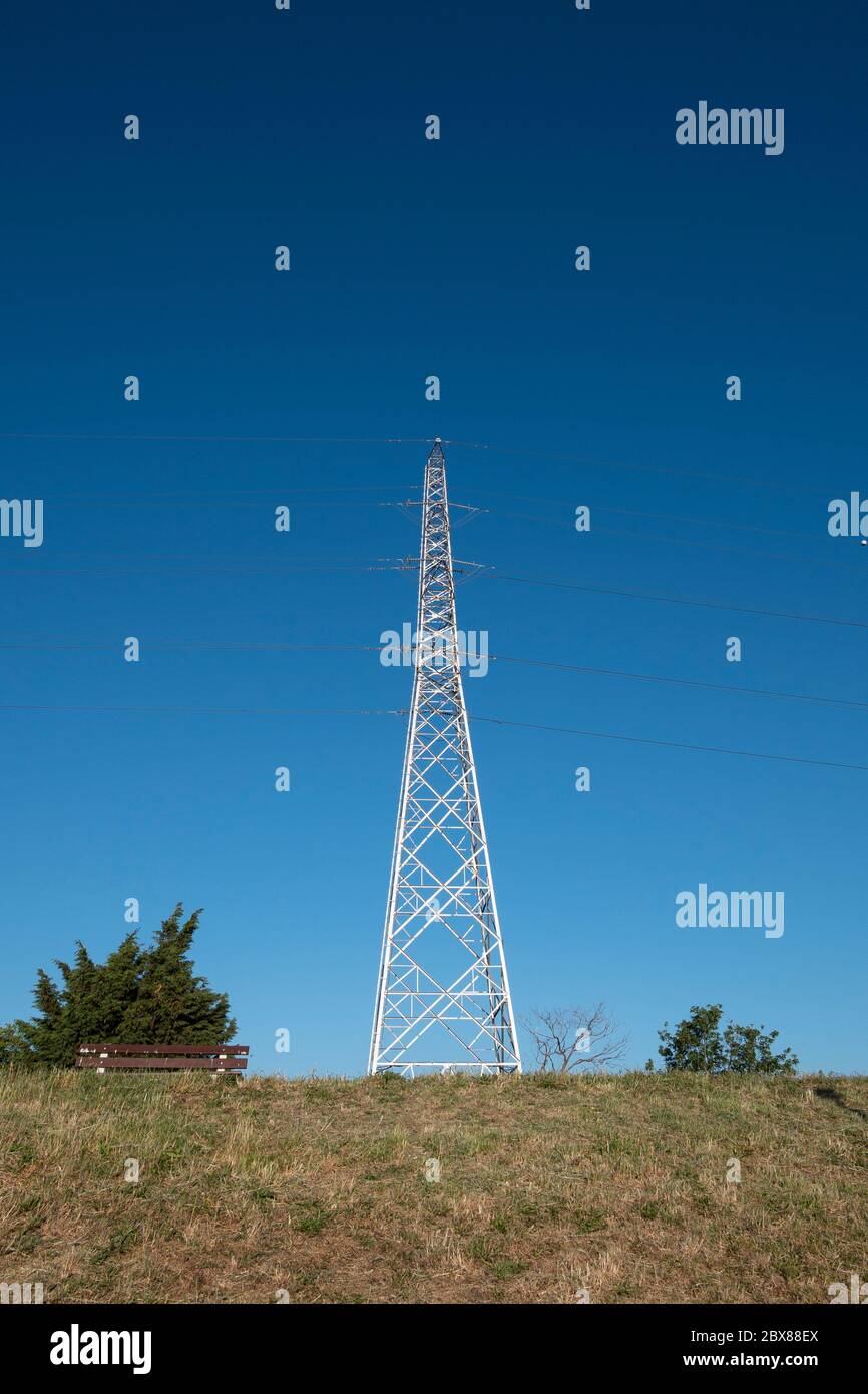 Strommast auf einem grünen Hügel mit blauem Himmel Stockfoto