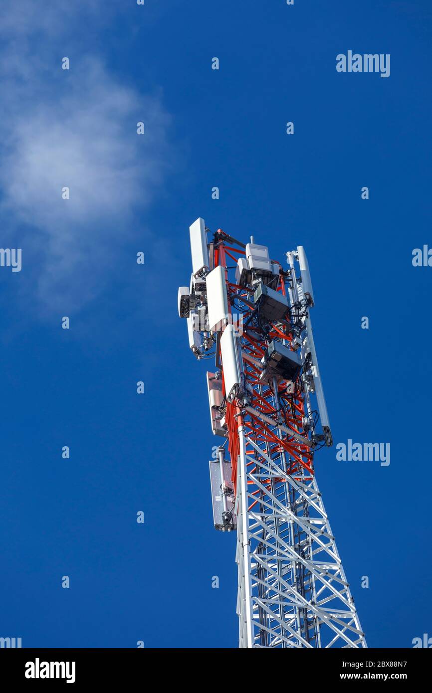 Oberseite eines metallischen rot-weißen selbst unterstützenden zellularen Netzwerk Antennenturm mit mehreren Antennen gegen blauen Himmel, Finnland Stockfoto