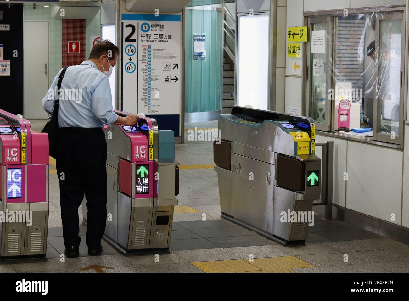 Der Passagier nutzt die IC-Karte am Bahnhof der Tozai-Linie. Menschen tragen Gesichtsmasken & ein Plastikschild bedeckt das Ticket-Gate-Fenster wegen Coronavirus. Stockfoto
