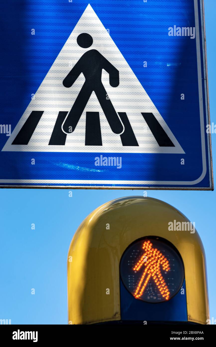Nahaufnahme eines Wegweigers und einer orangefarbenen Fußgängerampel. Trient, Trentino-Südtirol, Italien, Europa Stockfoto