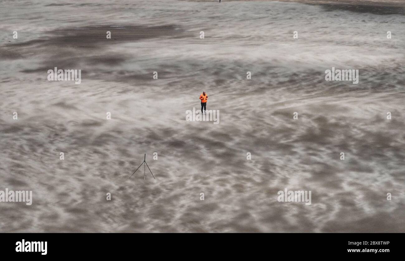 Ein Mann läuft an einem windigen Strand in Tynemouth Longsands entlang, da Großbritannien voraussichtlich am Wochenende mit starken Regenschauern, starken Stürmen und kälteren Temperaturen heimgesucht wird, wobei die Briten gewarnt werden, keine Versammlungen in die Wohnung zu verlegen. Stockfoto