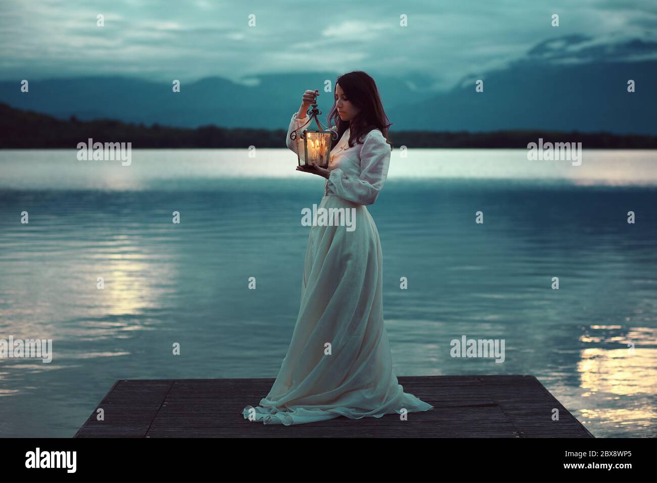 Traurige Braut am See Pier mit Laterne. Romantisch und surreal Stockfoto