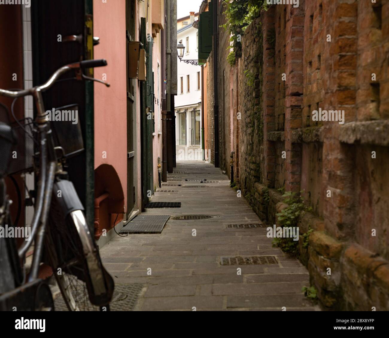 Tourismus in Venetien und Point of Interest zwischen den engen Gassen und Maritme Häuser zum Hafen von Caorle mit Fahrrädern und bunten Häusern. Stockfoto