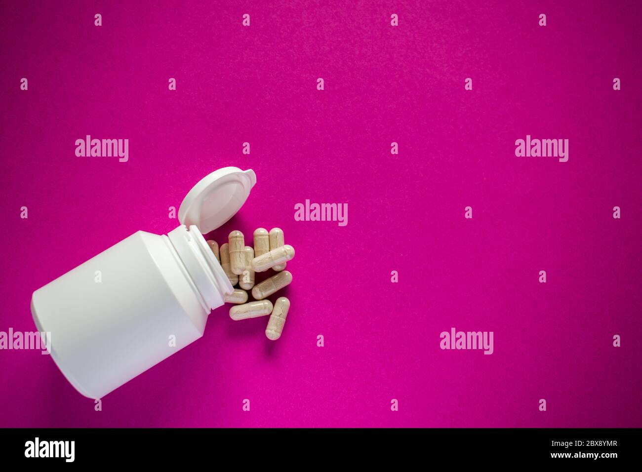 Medizinische Pillen Tabletten mit weißen Pille Flasche auf rosa Hintergrund Stockfoto