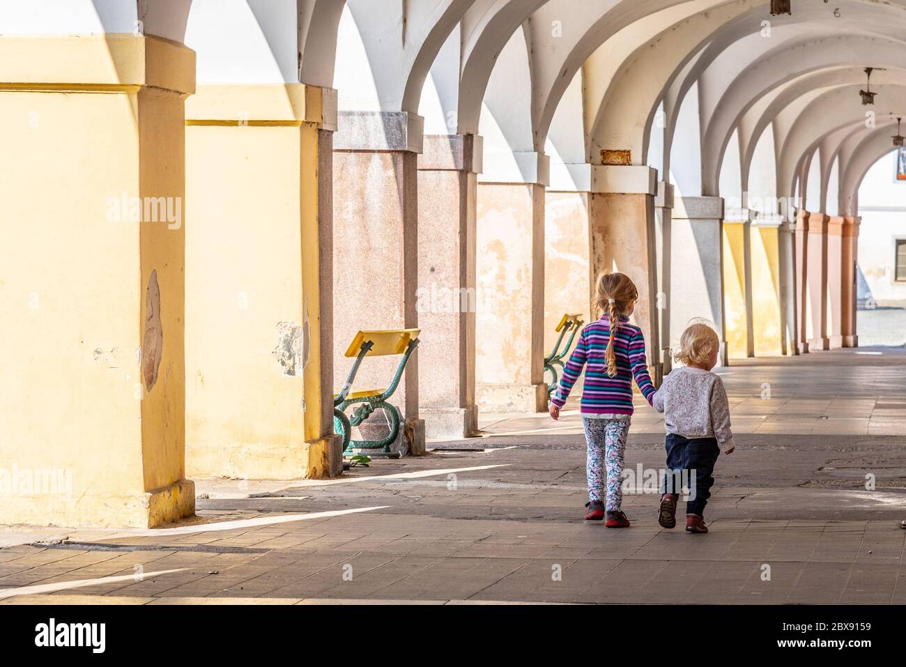 Zwei kleine Kinder gehen Hand in Hand in der Altstadt-Arkadenstraße. Familie Liebe und Freundschaft Thema. Stockfoto