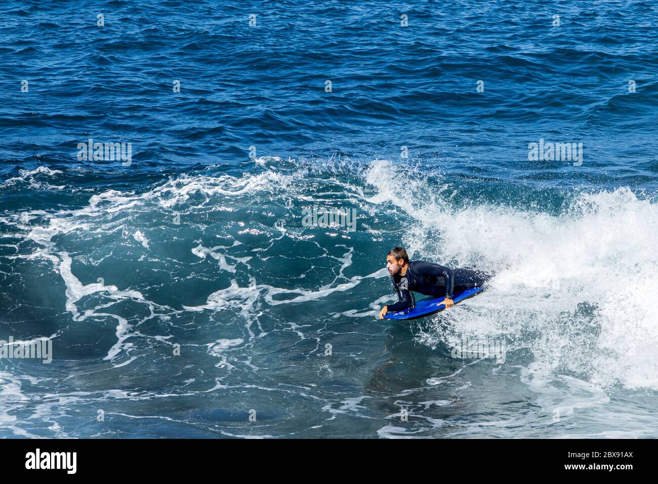 Ein Bodyboarder fährt in Phase 2 der Deeskalation des Covid 19, Corona-Virus, Notstand, die Brandung in den Strand. Ab Montag werden die Inseln in Phase drei übergehen. Playa de La Arena, Puerto Santiago, Teneriffa, Kanarische Inseln, Spanien. Juni 2020. Stockfoto