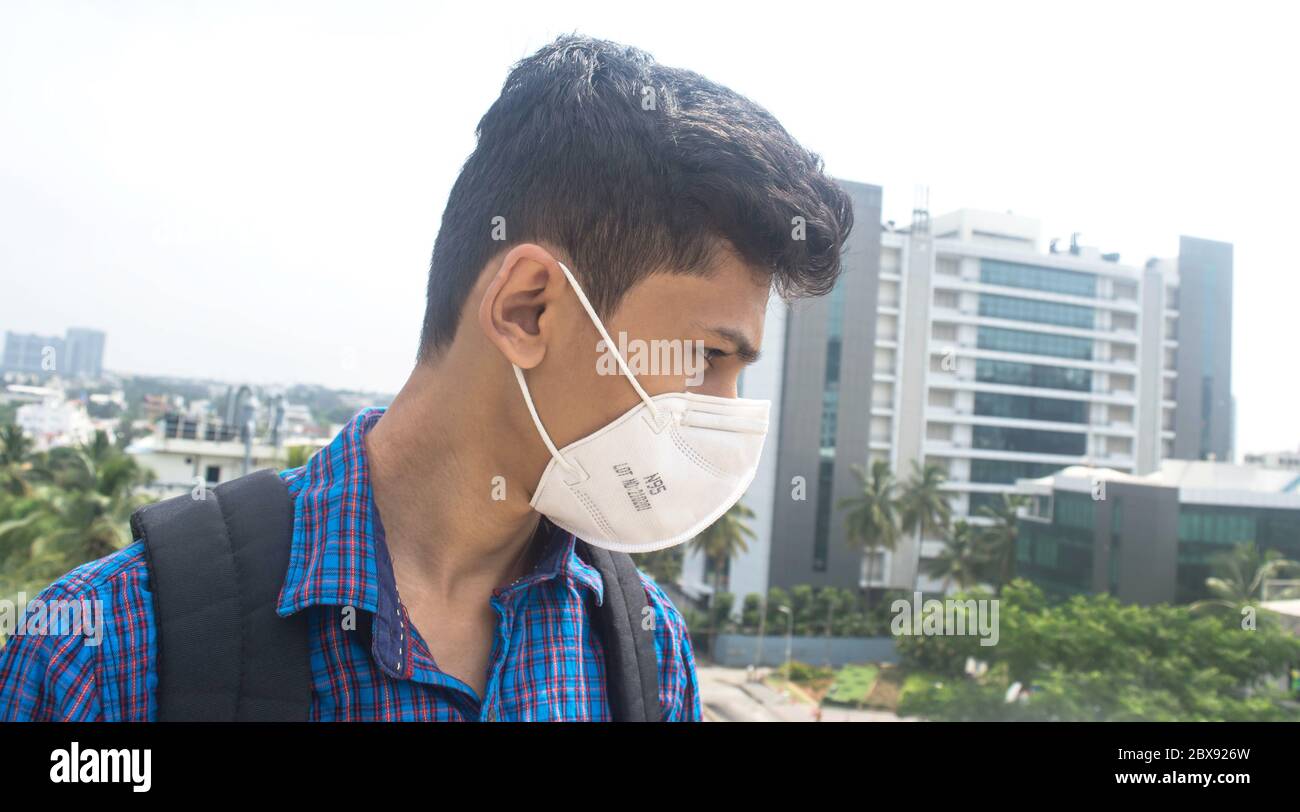 Seitenansicht des jungen Mannes mit chirurgischen Gesichtsmaske auf einem Hintergrund der Firma. Stockfoto