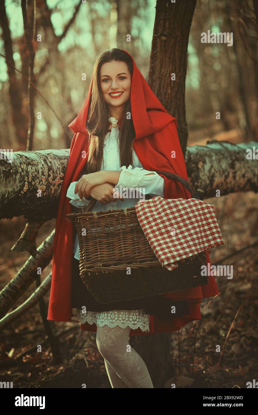Schöne und lächelnde kleine rote Reithaube posiert im Wald Stockfoto