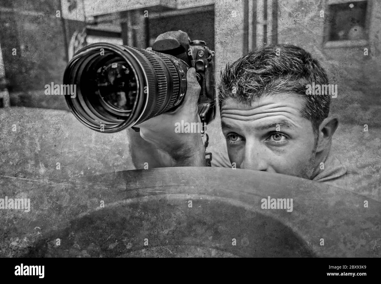 Urban Hintergrund Lifestyle lustiges Porträt von jungen Paparazzi Fotograf Mann in Aktion hinter Stadt Papier Korb Stalking für Dreharbeiten exclusiv versteckt Stockfoto