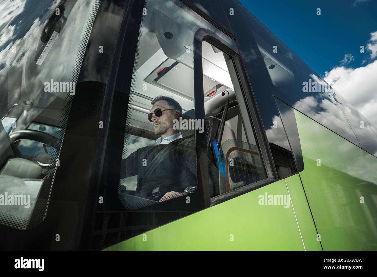 Moderne Bus Coach Driver Job. Kaukasische Männer Hinter Internationalen Bus Lenkrad. Thema Transportbranche. Stockfoto