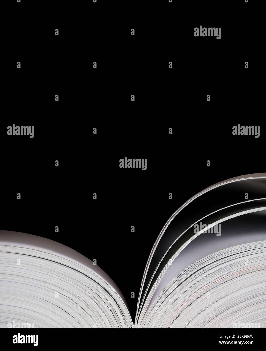 Buch auf schwarzem Hintergrund öffnen. Platz für Text auf einem isolierten schwarzen Bereich über dem Buch. Vertikales Bild Stockfoto