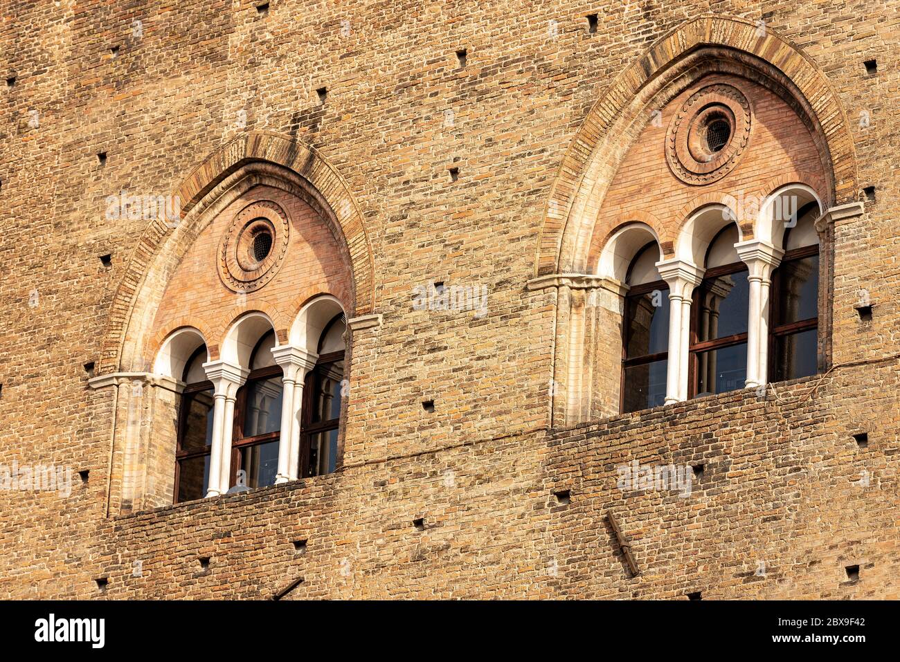 Zwei Doppelfenster (dreifach - Dreifachlanze) des mittelalterlichen Palazzo Re Enzo (König Enzo Palast, 1245) auf der Piazza del Nettuno, Bologna. Italien. Stockfoto
