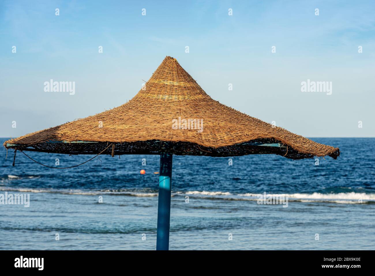 Nahaufnahme eines Strohstrandschirms mit dem Roten Meer im Hintergrund, in der Nähe von Marsa Alam, Ägypten, Afrika Stockfoto