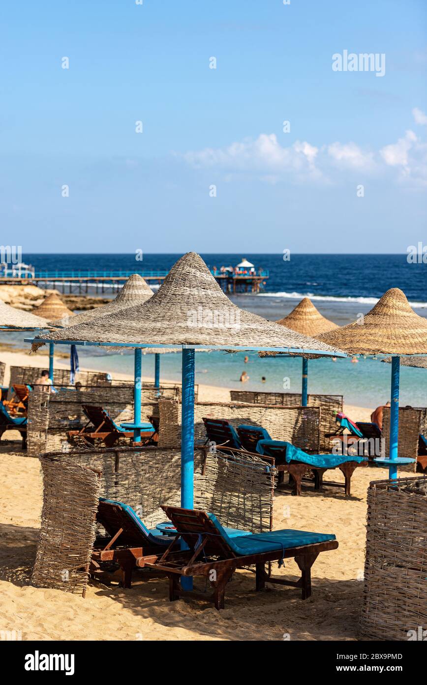 Gruppe von Stroh Sonnenschirme und Liegestühle in einem roten Meer Sandstrand, Ferienort in der Nähe von Marsa Alam, Ägypten, Afrika Stockfoto