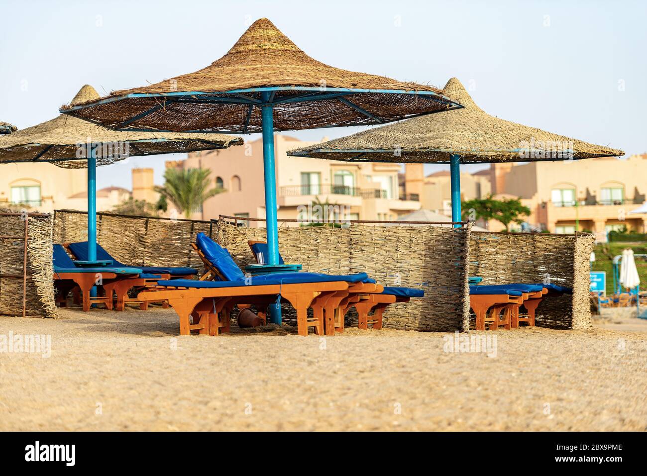 Gruppe von Stroh Sonnenschirme und Liegestühle in einem roten Meer Sandstrand, Ferienort in der Nähe von Marsa Alam, Ägypten, Afrika Stockfoto