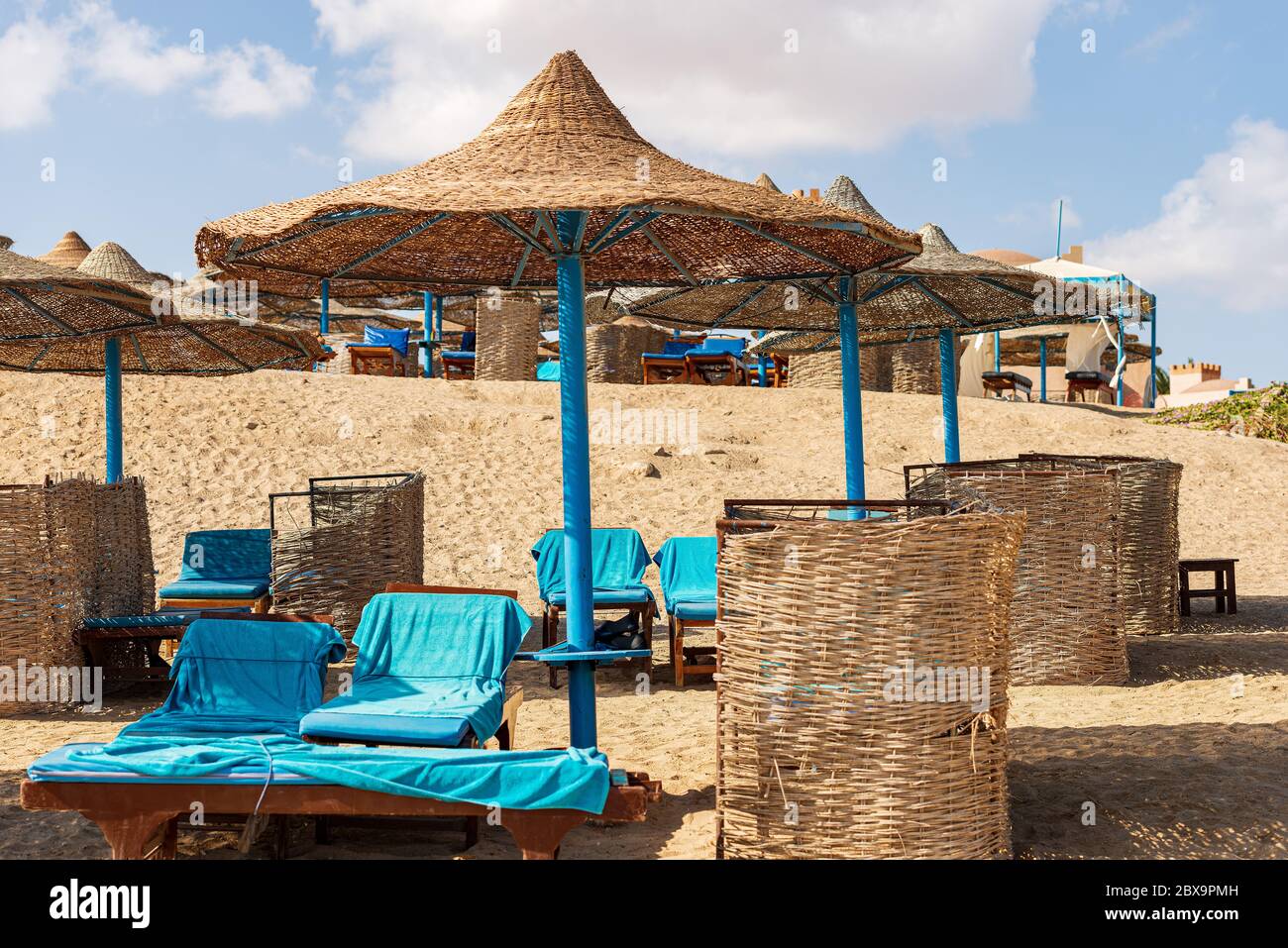 Gruppe von Stroh Sonnenschirme und Liegestühle in einem roten Meer Sandstrand, Ferienort in der Nähe von Marsa Alam, Ägypten, Afrika Stockfoto