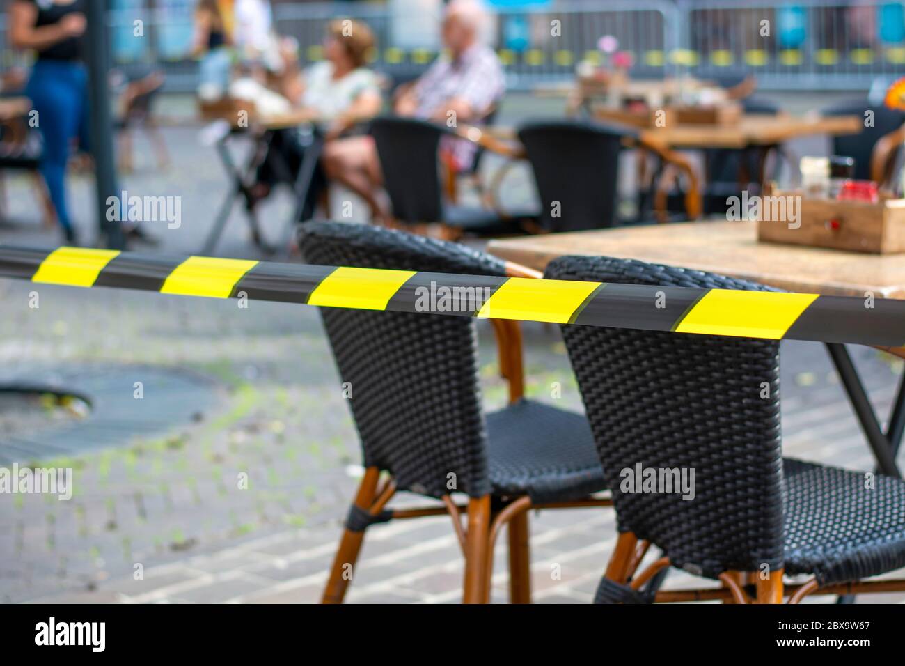 Terrassen in der Stadt wieder geöffnet. Sicherheitsbarrieren auf der Terrasse sorgen dafür, dass während des Coronavirus sichere soziale Distanz zwischen Tischen und Stühlen gehalten werden kann Stockfoto