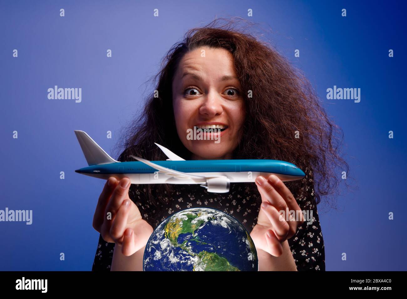 Mädchen mit einem Flugzeugmodell in den Armen über einem Erdball. Konzept der Airline Hilfe. Stockfoto