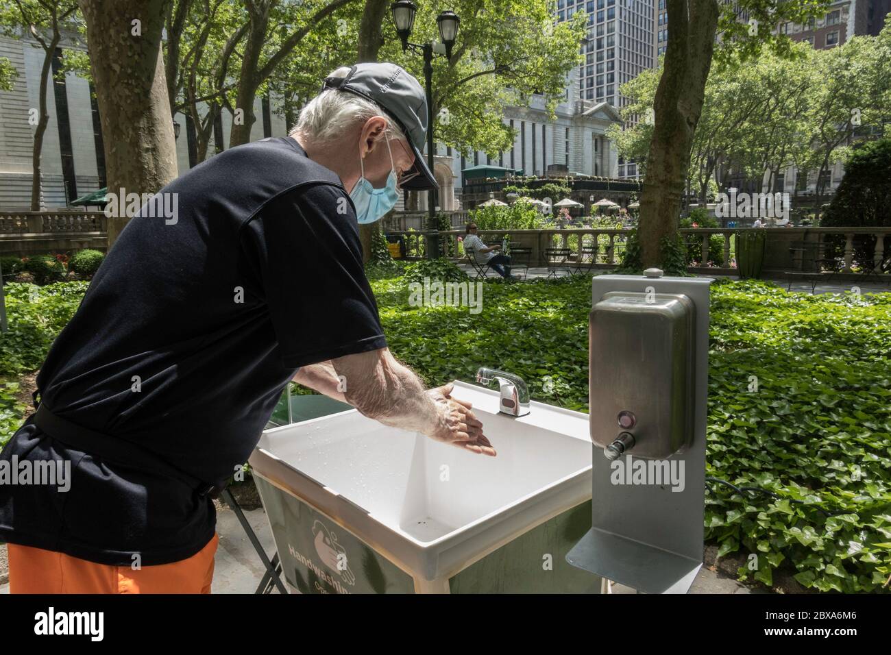 Ältere Mand in Gesichtsmaske verwendet eine kostenlose Händewaschstation im Bryant Park, New York City, USA Stockfoto