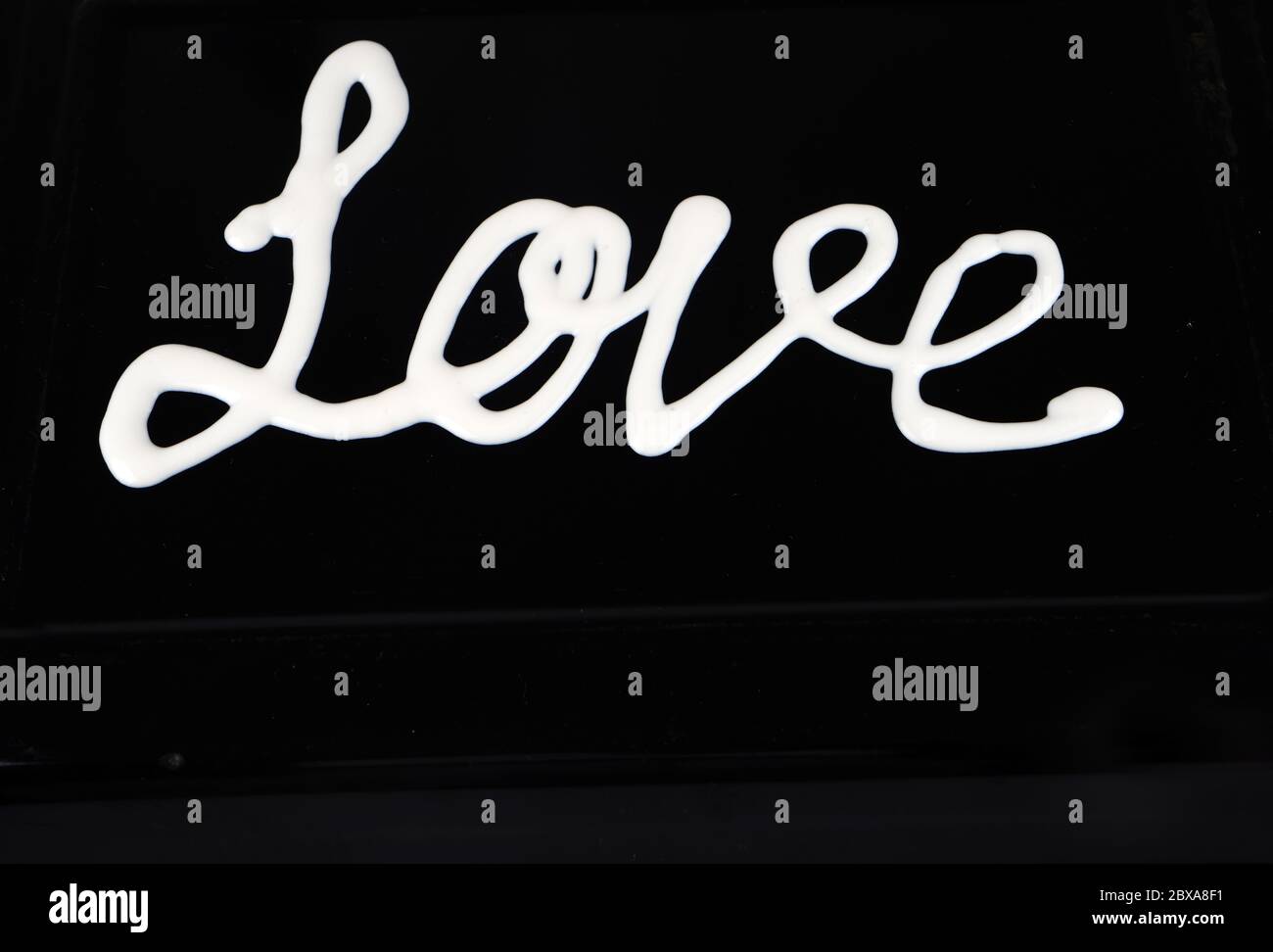 Handgeschriebene Liebesbuchstabierung auf schwarzem Hintergrund Stockfoto