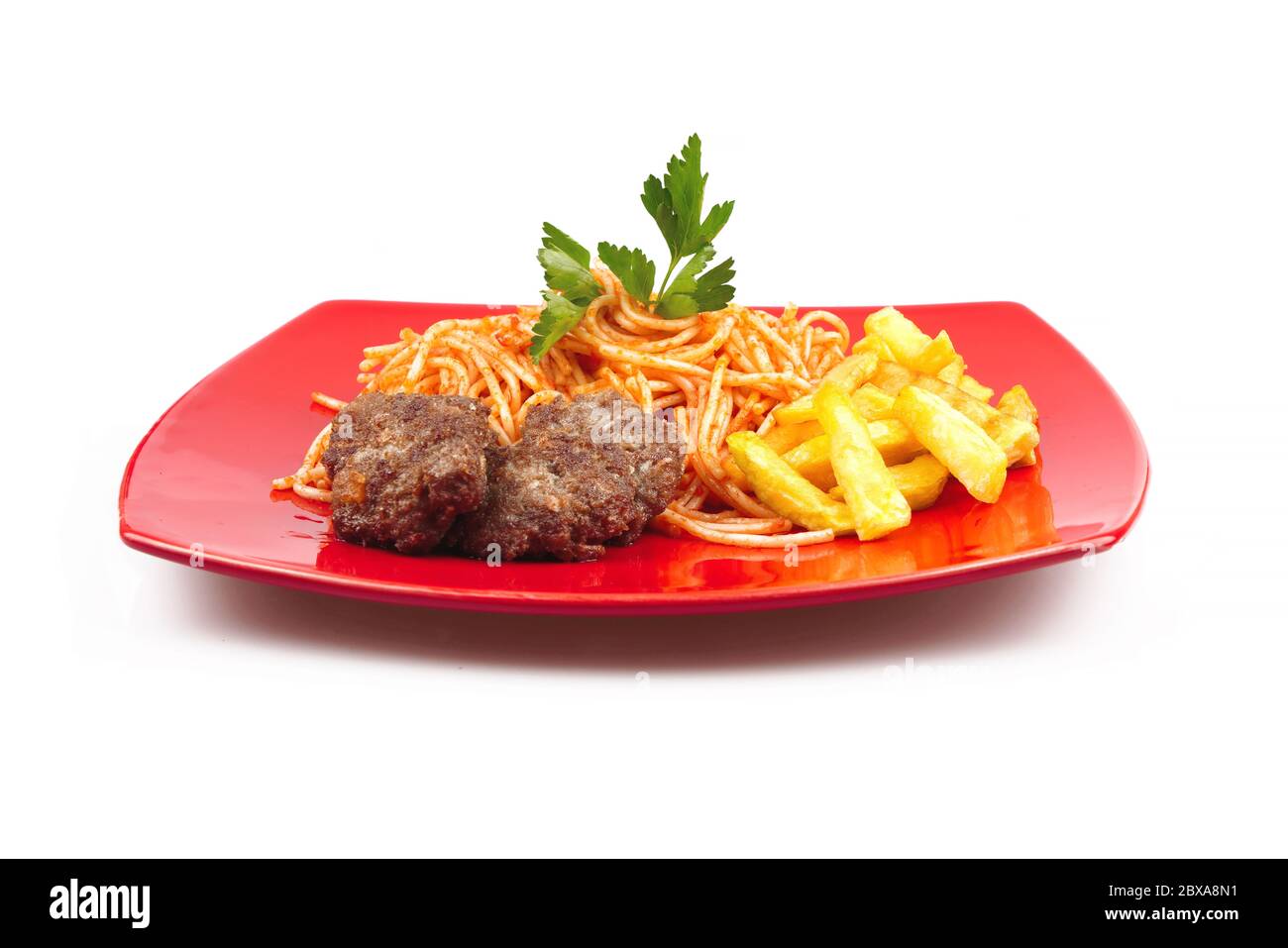 Pasta, Fleischbällchen und Kartoffeln auf einem roten Teller auf weißem Hintergrund Stockfoto