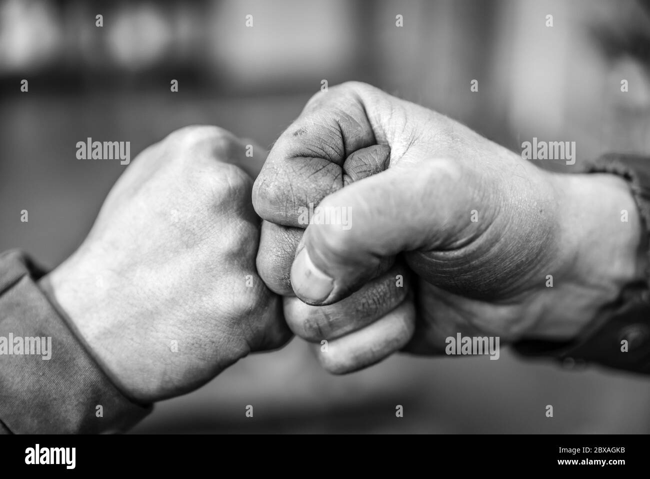 Zwei Kollegen begrüßen sich mit einem Handschlag und verwenden ihre Fäuste als Symbol für Kameradschaft, Freundschaft und Solidarität. Stockfoto