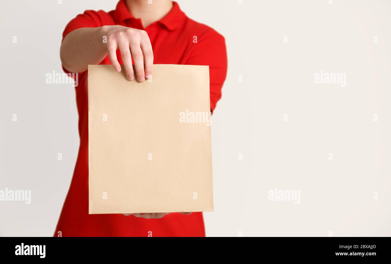 Beauftragen Sie zerbrechliche Gegenstände mit dem Kurier. Kurier hält Papiertüte an den Kunden Stockfoto