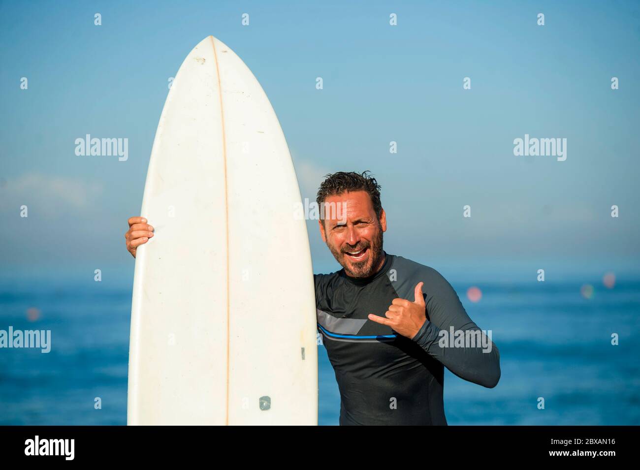 Lifestyle Strandportrait von schönen und attraktiven Surfer Mann in Neopren  Badeanzug halten Surfbrett posiert kühl nach dem Surfen genießen  Sommerwasser Stockfotografie - Alamy