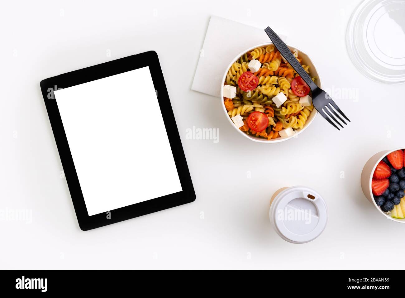 Essen in wegnehmen Boxen auf weißem Tisch mit Tablette mit leerem Bildschirm Stockfoto