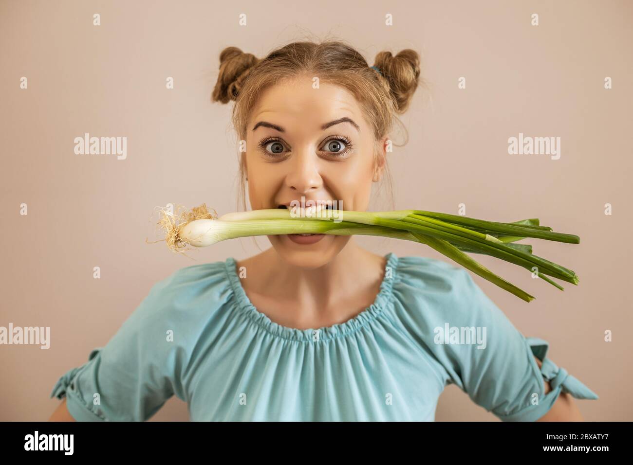 Porträt von niedlichen verspielten Frau essen junge Zwiebel.Toned Bild. Stockfoto