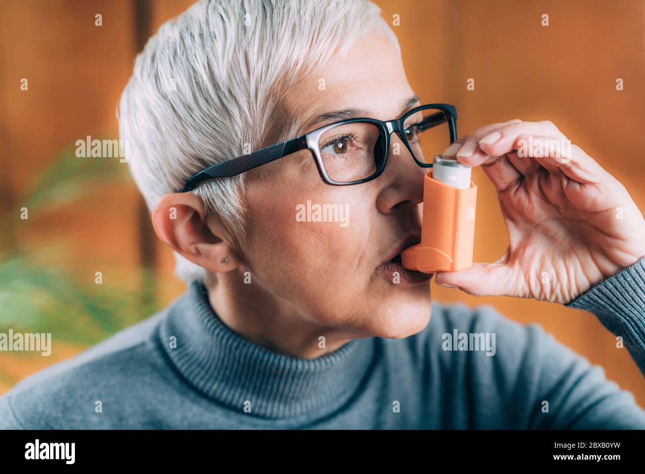 Ältere Frau inhaliert Medizin von Asthmapumpe Stockfoto