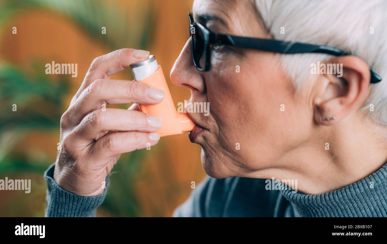 Ältere Frau mit Asthma-Inhalator mit Verlängerungsschlauch Stockfoto