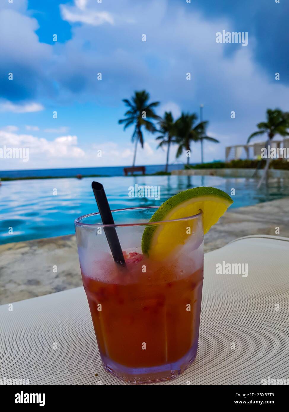 Passionsfrucht-Alkoholiker-Cocktail mit Limette und Palmen im Hintergrund in den TRS Hotels, Grand Palladium Resort, Cancun, Mexiko. Stockfoto