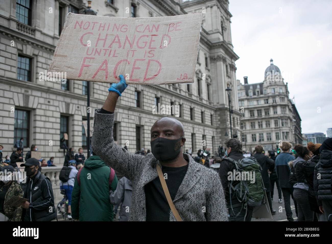 Ein Protestler geht an institutionellen Gebäuden im Zentrum Londons vorbei und hält ein Plakat gegen systemischen Rassismus in Großbritannien. Stockfoto