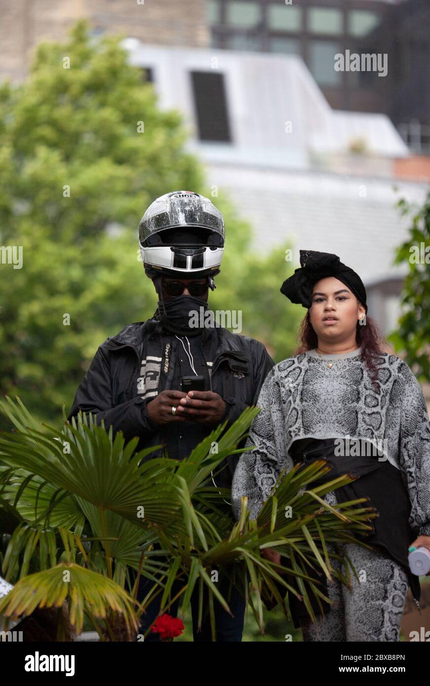 Mann, der einen Helm trägt und ein Handy benutzt, steht neben einer Frau beim Protest der Black Lives Matter UK, Parliament Square, London, England, UK Stockfoto