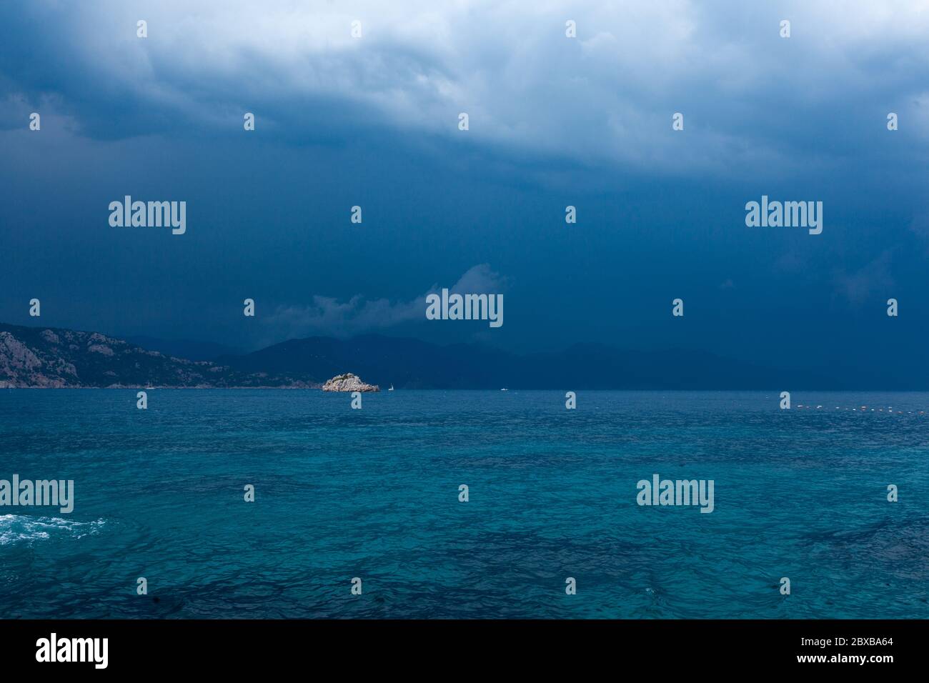 Blaues Meer und Wolken in einem blauen stürmischen Himmel mit Bergen im Hintergrund. Hochwertige Fotos Stockfoto