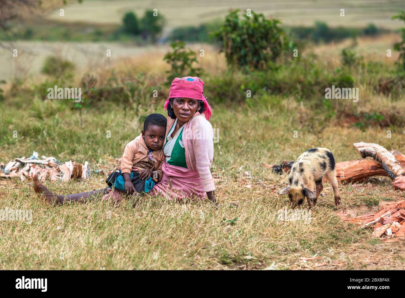 Müde afrikanische Frau mit Kind auf dem grünen Feld sitzen. Zentralmadagagagaga Stockfoto