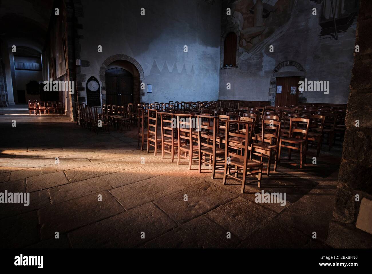 Holzstühle und Knienhocker im Transpet der Kirche St. Melaine mit einem Lichtstrom, der die Stühle und Nische beleuchtet Stockfoto