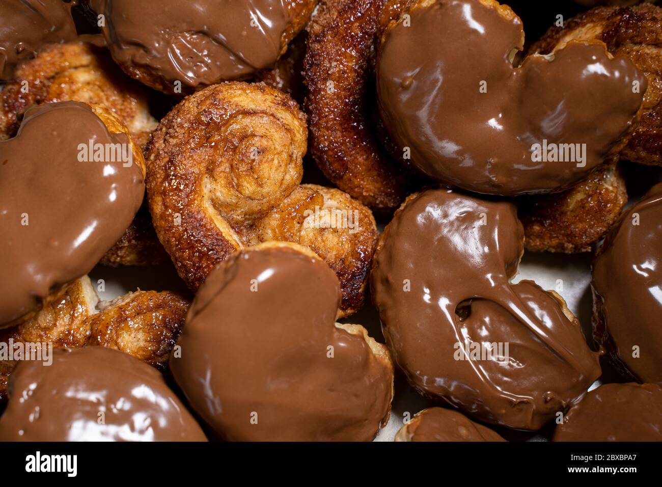 Palmier Kekse mit Schokolade überzogen. Nahaufnahme von oben. Herzförmiges Blätterteig, Schweinehaar, Palmenblätter, Elefantenohren, französische Herzen, Schuh Stockfoto