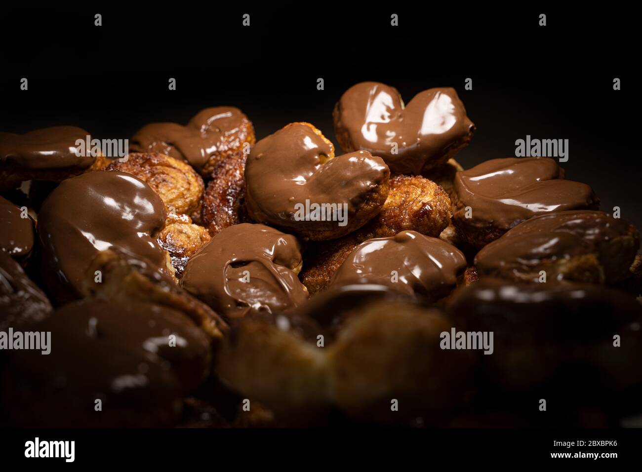 Schokolade palmier Kekse low light. Herzförmiges Blätterteig, Schweinehaar, Palmenblätter-Kekse, Elefantenohren, französische Herzen, Schuhsohlen. Stockfoto