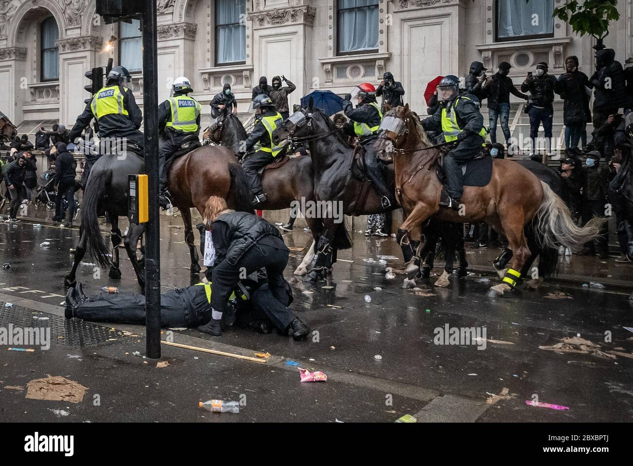 Ein Polizist liegt bewusstlos, nachdem er während der Zusammenstöße, die während der Proteste von Black Lives Matter in Westminster ausbrachen, von ihrem Pferd geworfen wurde. Fackeln, Flaschen und andere Trümmer wurden auf die Polizei geworfen, nachdem Tausende von Aktivisten und Unterstützern der Black Lives Matter auf dem Parliament Square eingepackt waren. London, Großbritannien. Stockfoto