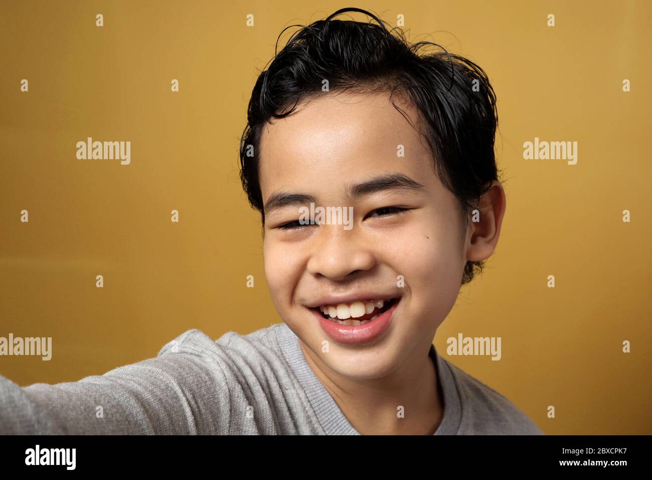 Nahaufnahme von jungen kleinen asiatischen Kind, die ein Selfie-Foto über gelben Hintergrund, zeigt glücklich lächelnd fröhlichen Ausdruck Stockfoto