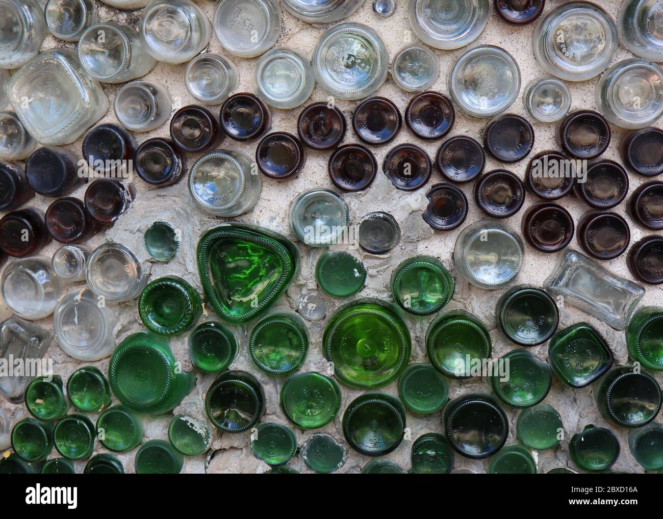 Farbige und klare Flaschen in Zement platziert bilden eine Wand. Stockfoto